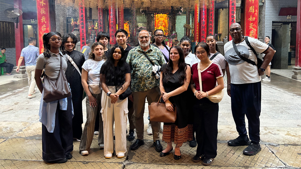 Ten Adelphi students stand in a colorful street market in Southeast Asia, with Sentwali Bakari, PhD, on far right