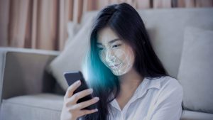 A woman with long dark hair looking at her smartphone with her face overlaid with a digital grid