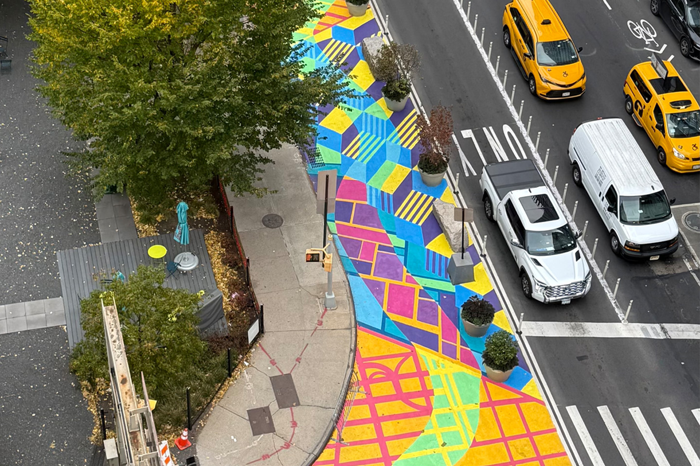 The mural seen from above, showing the work’s colorful, geometric designs. Next to the mural are cars waiting to enter the Holland Tunnel.