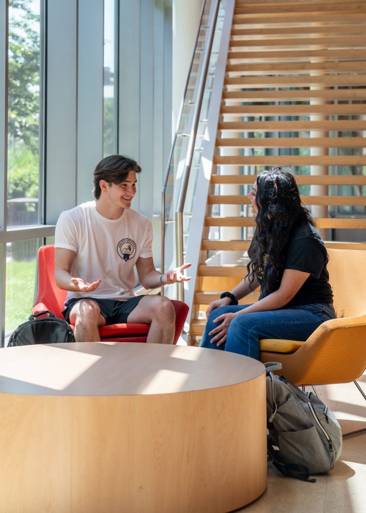 Two students study and talk in the Nexus Building at Adelphi.