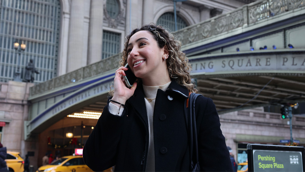 A young woman talking on her cellphone walks past Grand Central Station.