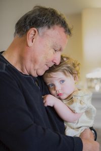 Mark W. Jordan ’63 holding and embracing his young granddaughter indoors.