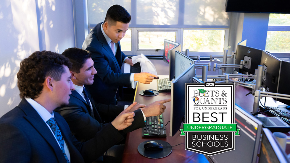 Three male business students in professional suits work collaboratively in a high-tech finance lab with 2026 Best Undergraduate Business Schools badge.