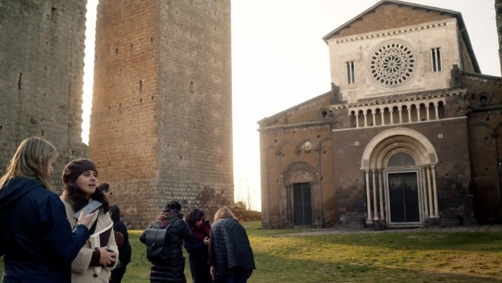 Adelphi students talking in front of San Pietro in Tuscania, Italy.