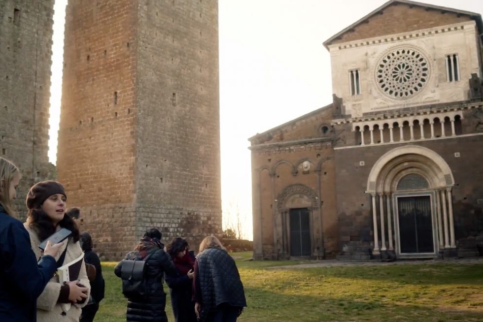 Adelphi students talking in front of San Pietro in Tuscania, Italy.