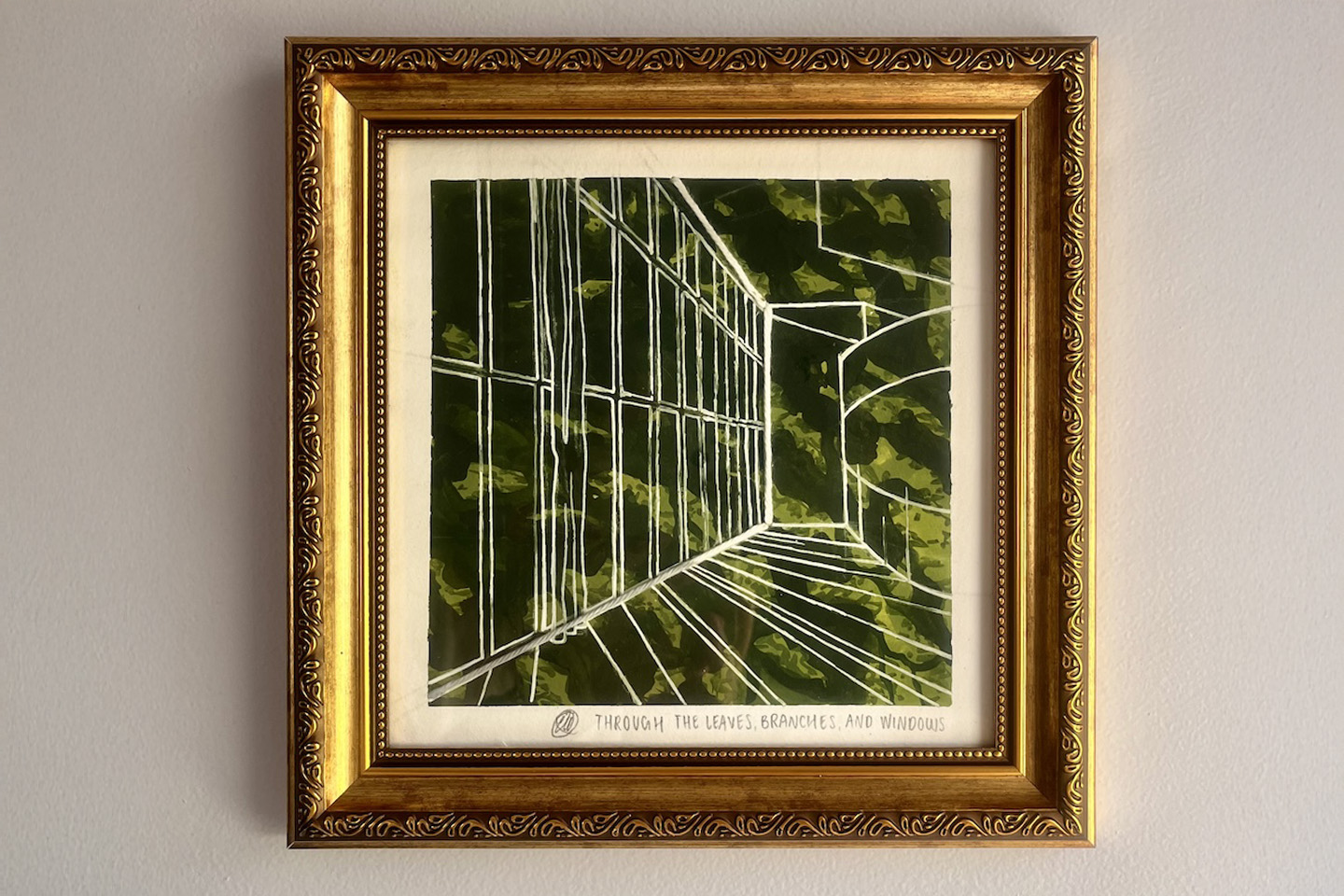 A square artwork featuring a background of layered greens in an ornate gold frame hangs on a light-colored wall. A handwritten title beneath the image reads, “Through the Leaves, Branches, and Windows.”