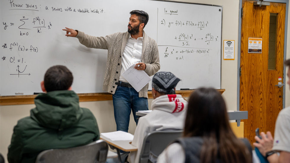 Dr. Venkatesh is seen at the whiteboard at the front of a classroom of students.