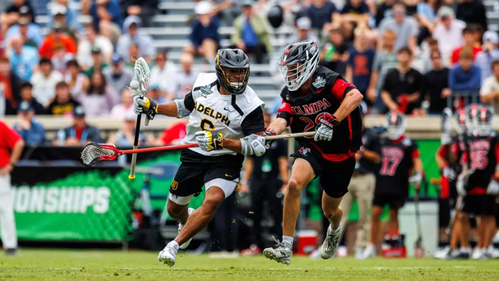 Lewis runs to his right cradling the ball as a University of Tampa player defends him.