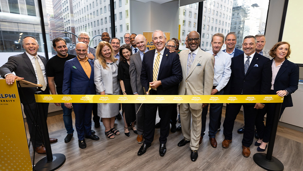 A group of people in business attire smiling at a ribbon-cutting event 