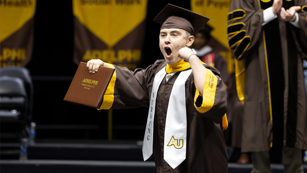 A male nursing students gives a shout onstage after receiving his diploma.