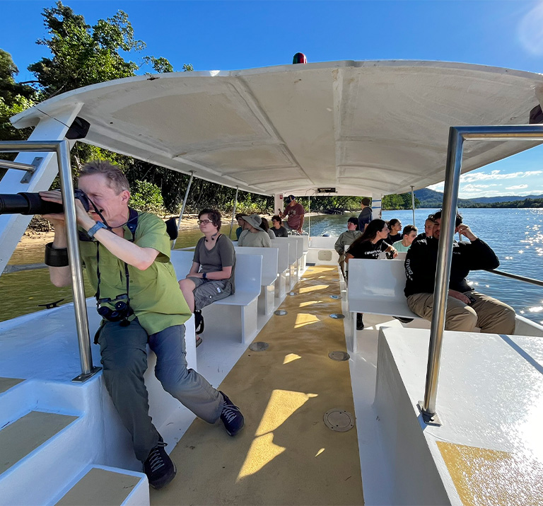 A professor with a long-lens camera leans out of tour boat to get a photo.