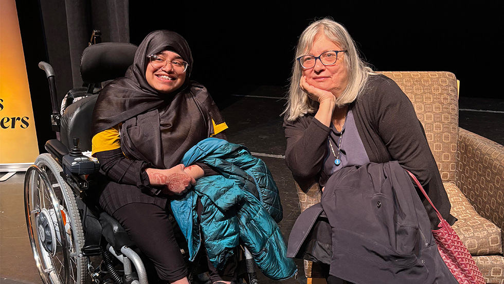 Afra Masud, in her wheelchair and wearing a hijab, next to a seated Alice Hoffman