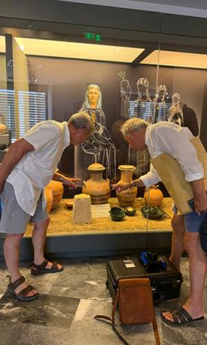 Professor Agelarakis and his colleague examine pottery displayed in a museum showcase. 
