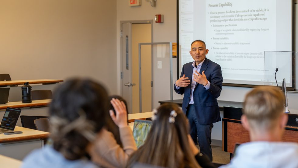 Professor Zhang teaching a classroom setting speaking to a group of students 