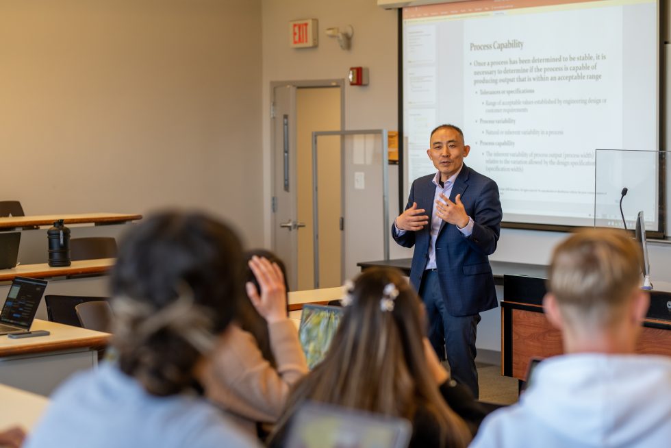 Professor Zhang teaching a classroom setting speaking to a group of students 