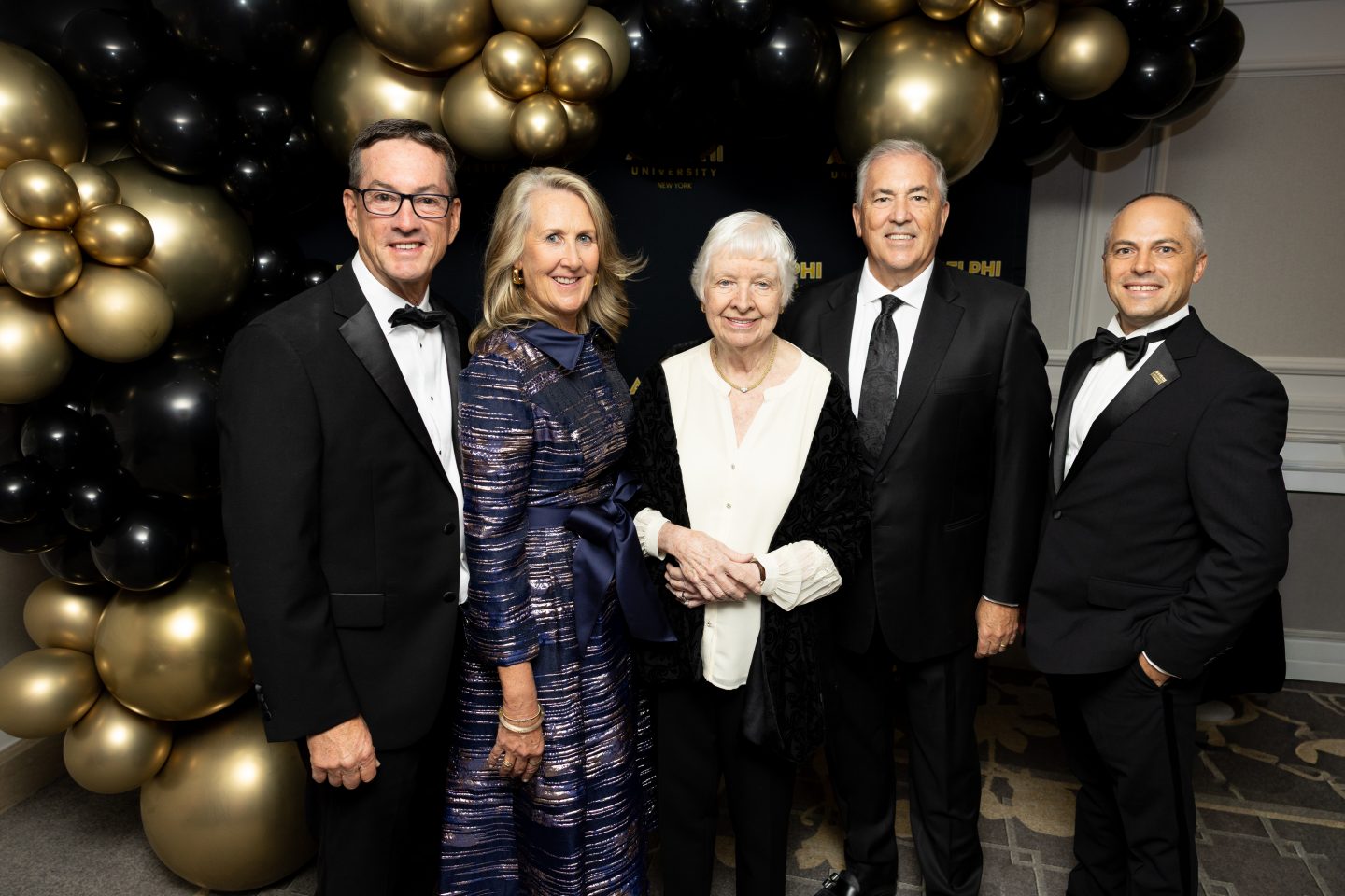 Judith Ammerman, MA ’64, MS ’73 (center), who established a $500,000 scholarship for first-generation students at the 2026 Adelphi University Gala, is joined by John and Lorraine Reynolds, President Michael Balboni ’81, JD (second from right), and Vice President Thomas A. Kline, EdD (far right).
