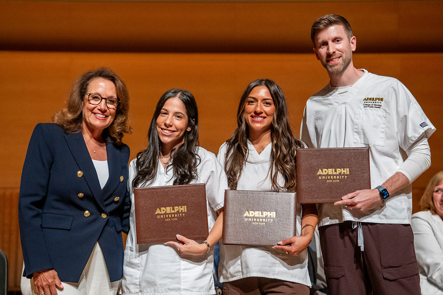 Two nursing staff members congratulate three students who won academic awards.