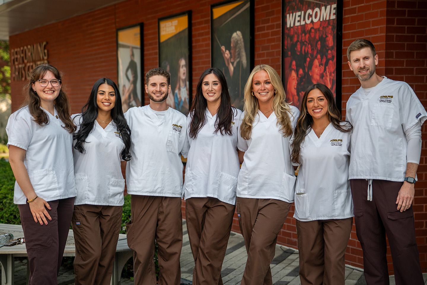 A lineup of seven students, two men and five women, stand in uniform before the ceremony.