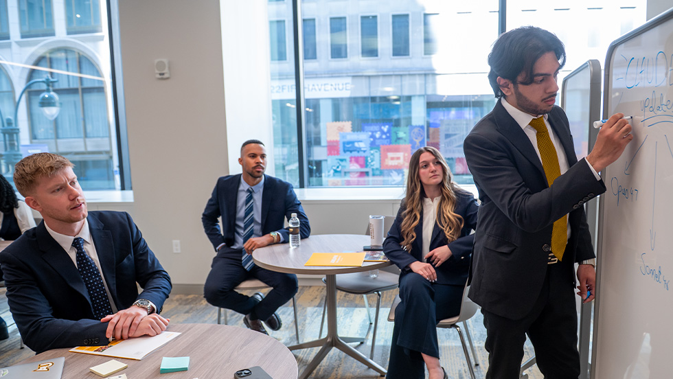 Four individuals in business attire collaborating on a presentation in a modern work space
