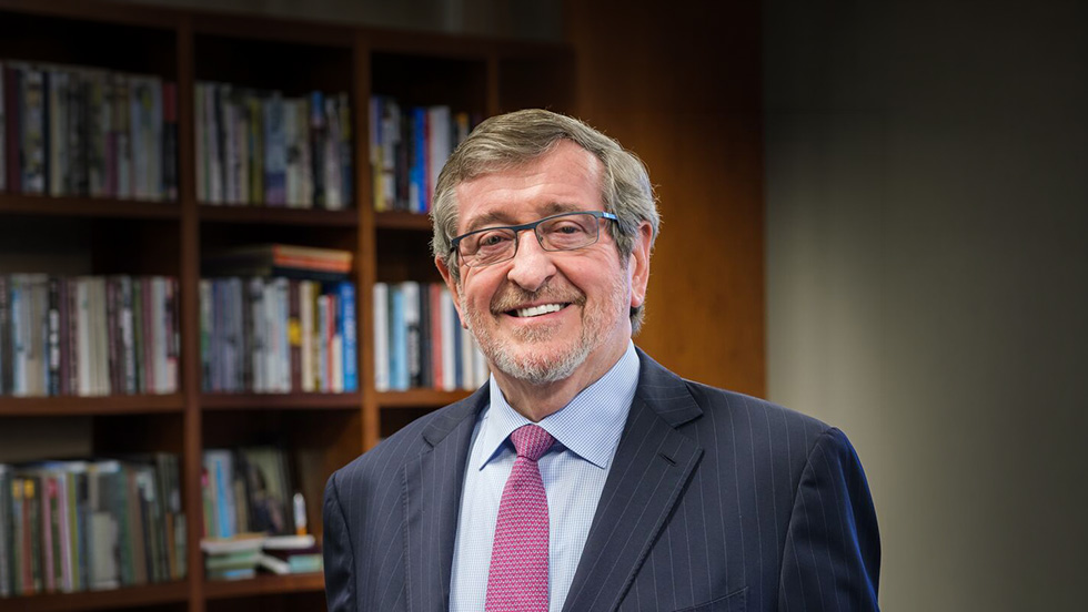 Headshot of Michael Dowling standing in front of a bookshelf