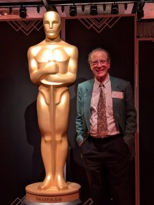 O'Neill stands next to a larger-than-life version of the Oscars statuette