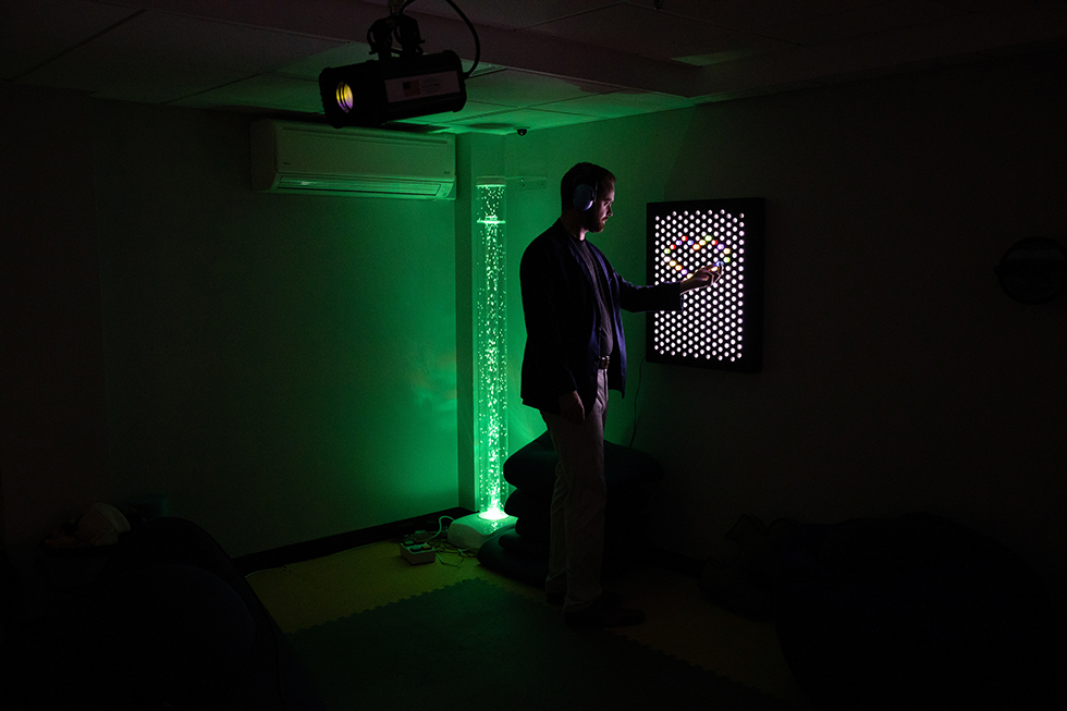 A student plays with a lighted pegboard in the soothing, dimly lit sensory room.