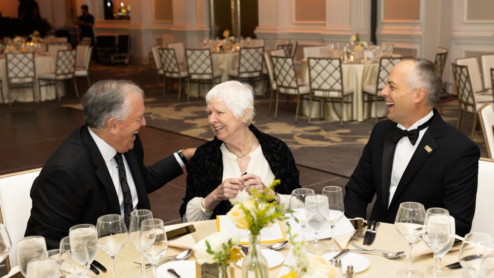 Michael Balboni, Judith Ammerman and Thomas Kline smile together at a table during Adelphi’s 2026 Gala.