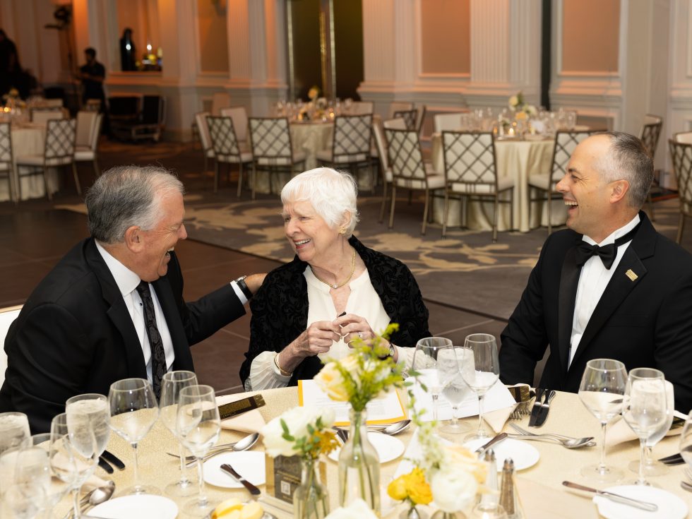 Michael Balboni, Judith Ammerman and Thomas Kline smile together at a table during Adelphi’s 2026 Gala.